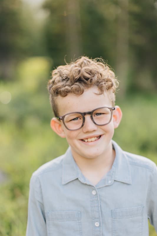 Happy child with curly hair wearing glasses — a Blinc Eyecare patient