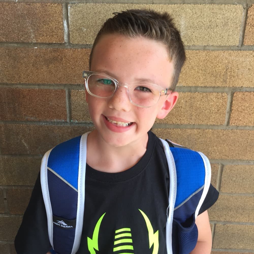 Happy child wearing glasses and a backpack — a Blinc Eyecare patient